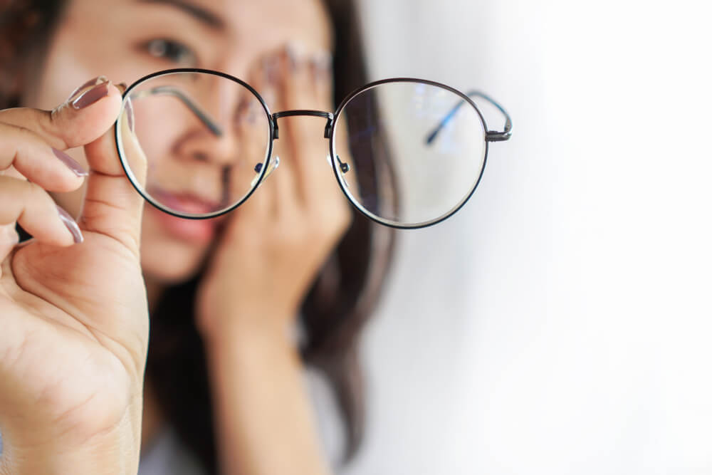 Frau mit Brille im Fokus die Sich die Augen reibt